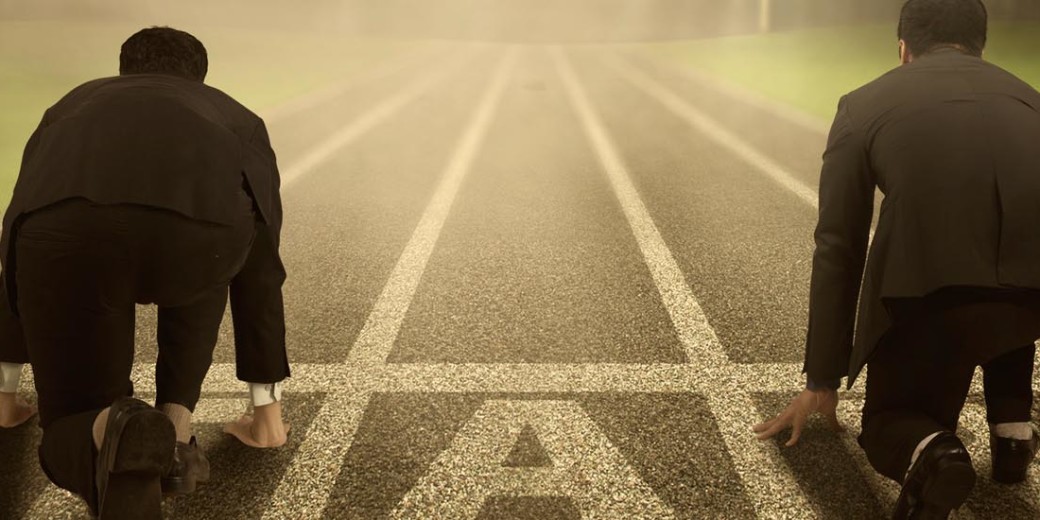 A person in business attire standing at the start line on a racetrack.