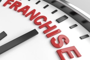 Close-up of a clock with the word 'FRANCHISE' in red letters.