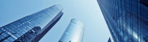 Two modern glass skyscrapers against a clear blue sky.